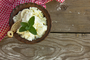 dairy product cottage cheese in brown ceramic bowl. Curd in brown bowl on blue napkin. Fresh cottage cheese in bowl with spoon on vintage wooden tabledoor