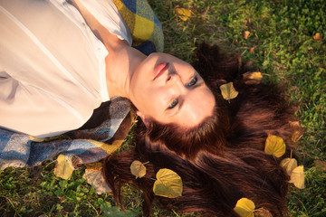 A large Portrait of a Mature woman lying on the ground, autumn leaves scattered in her hair.