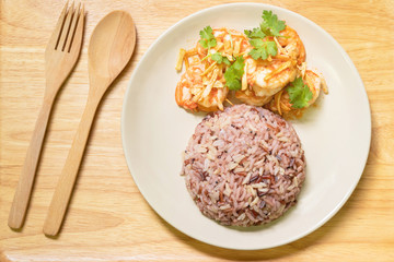 Stir fried shrimp with garlic and coriander leaves serve with cooked mix riceberry, jasmine rice, brown rice and red rice. Top view with spoon and fork.