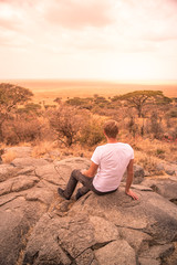 Fototapeta na wymiar Man at view point looking to the bush savannah of Serengeti at sunset, Tanzania - Safari in Africa