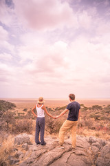 Young couple at view point looking to the bush savannah of Serengeti at sunset, Tanzania - Safari in Africa