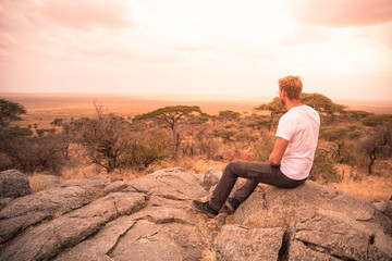 Naklejka na ściany i meble Man at view point looking to the bush savannah of Serengeti at sunset, Tanzania - Safari in Africa