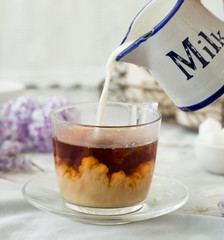 English tea with milk at the breakfast. Top view of a glass cup on wooden table. Morning time.