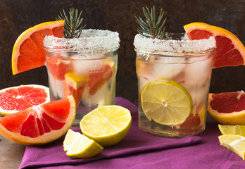 lemonade with ice, mint and paper straw in sparkling glasses on gray table background, christmas cocktail 