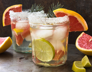 lemonade with ice, mint and paper straw in sparkling glasses on gray table background, christmas cocktail 