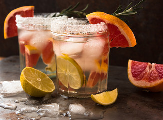 lemonade with ice, mint and paper straw in sparkling glasses on gray table background, christmas cocktail 