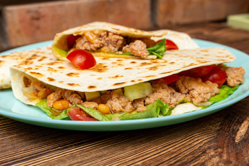 fajitos with minced meat vegetables in a corn tortilla on a blue plate dark wooden background. fast food traditional food concept