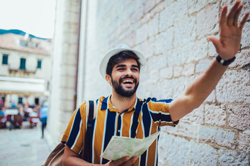 Handsome bearded tourist with backpack is making travel across city.