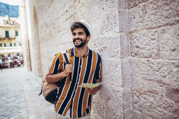 Handsome bearded tourist with backpack is making travel across city.