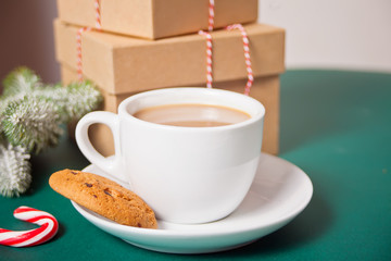 Cup of tea, candy cane, Christmas gift boxes, cookies on the green background