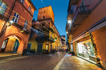 Cobblestone street illuminated with Christmas lights in Alba, Italy.
