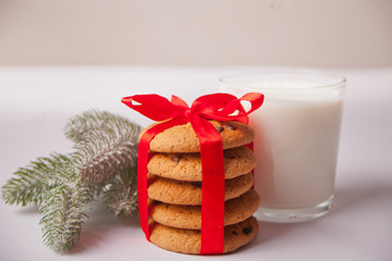 Glass of milk, cookies and Christmas tree branch on the white table