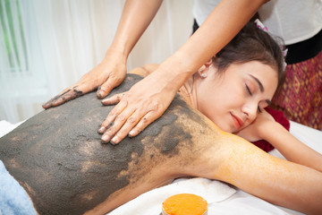 Asian woman getting a black salt scrub on her back beauty treatment in the health spa - 294552695