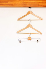 Wooden clothes hanger on rail in wooden open wardrobe 