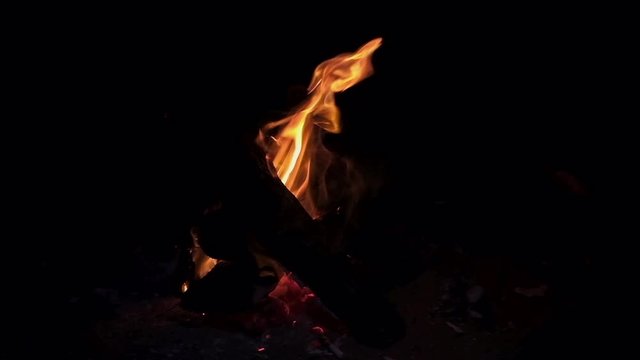 Wood fire burning in slowmotion at 120fps creating a relaxing camp fire atmosphere with cracking flames at night.