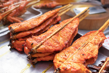 Grilled chicken marinated with curcuma on tray, ready to eat; Thai street food market. 