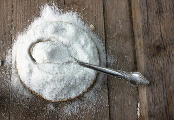 Crystals of shallow salt in a wooden bowl on a dark gray table. Background for advertising salt. Table salty. Salted food.