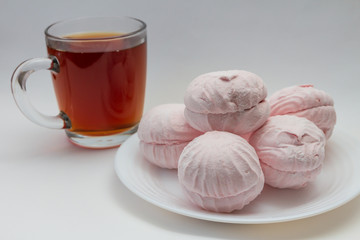still life pink marshmallow on a white plate and a cup of tea