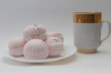 still life pink marshmallow on a white plate and a cup of tea