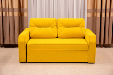 Modern yellow sofa and chair in room interior at home or hotel