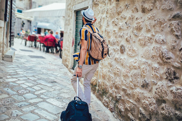 Handsome bearded tourist with backpack is making travel across city.