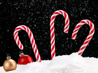 Three Xmas canes and balls in snow night