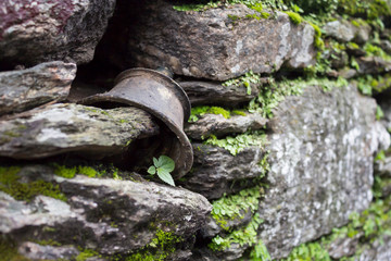 Ancient bell in a stone wall with plants. Close-up, copy space