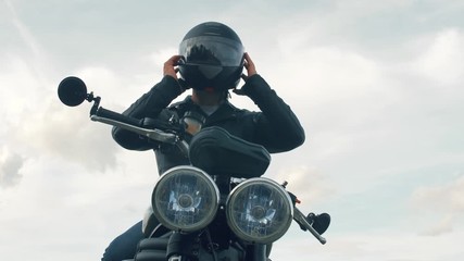Young man with a motorcycle wears a helmet on his head. Close up slow motion footage. 4k.