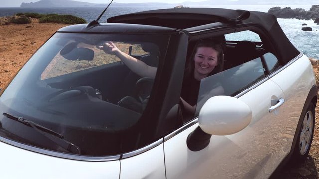 Woman opens roof in a cabriolet car, vacation on an island, car rental