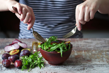 Selective focus. Chef preparing salad with arugula. Healthy salad with arugula and plums.