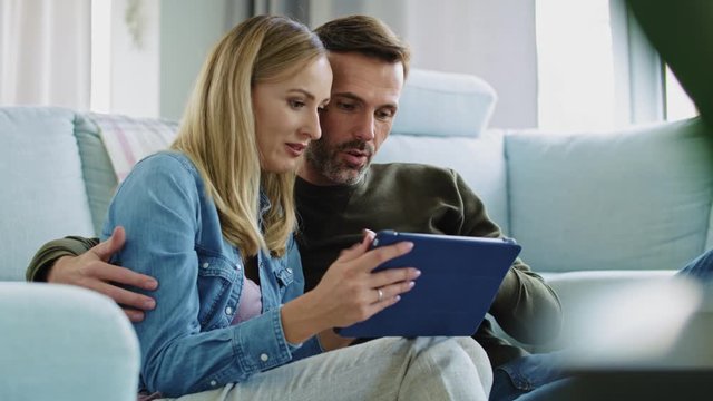 Loving couple using a tablet in living room