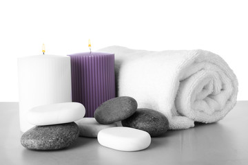 Fototapeta na wymiar Towel, candles and spa stones on table against white background
