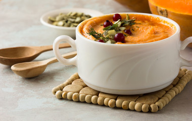 Pumpkin soup and organic pumpkins on rustic wooden table. Seasonal autumn food - Spicy pumpkin soup with thyme and pumpkin seeds.