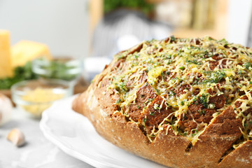 Tasty homemade garlic bread with cheese and herbs on grey table, closeup. Space for text