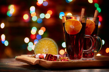 Christmas mulled wine red in a glass with a stick of cinnamon and a piece of orange on a background of twinkling lights