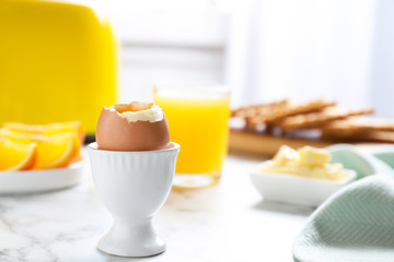 Cup with soft boiled egg on marble table, space for text. Healthy breakfast