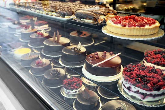 Different delicious cakes on display in cafe, view through window