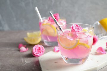 Delicious refreshing drink with lemon and roses on marble table