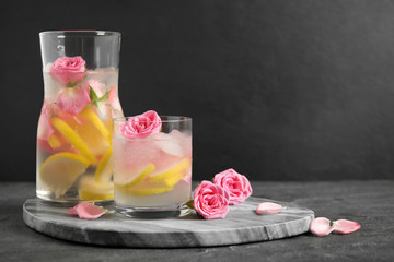 Delicious refreshing drink with lemon and roses on table against grey background. Space for text