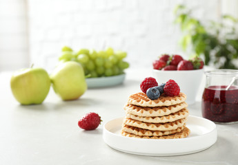 Delicious breakfast with waffles and berries on light table. Space for text