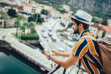 Handsome bearded tourist with backpack is making travel across city.