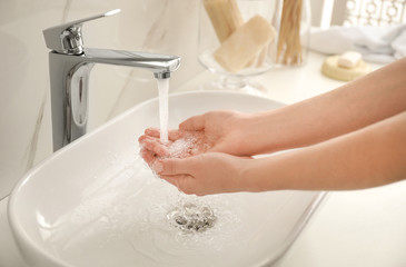 Woman washing hands indoors, closeup. Bathroom interior