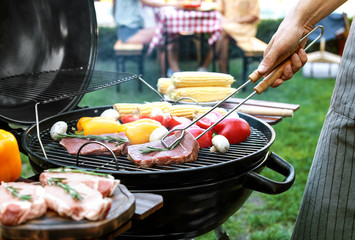 Man cooking on barbecue grill outdoors, closeup - obrazy, fototapety, plakaty