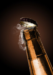 Cold wet bottle of chilled drink with drops. Opening of beer cap with the gas output.