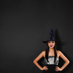 Beautiful woman wearing witch costume for Halloween party on black background, space for text