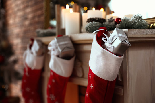 Decorative fireplace with Christmas stocking and gifts in stylish room interior