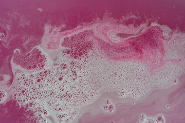 Pink colored water with white foam and bubbles