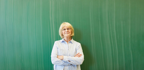 Alte Frau als Lehrer vor Tafel in Schule