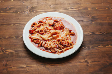 Squid tagliatelle with tomato sauce on a wooden table