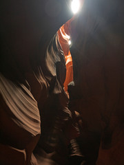 Fototapeta na wymiar Looking up at Low Antelope canyon, stunning view, eroded red sandstone walls, sun light falling on red canyon walls directly abov